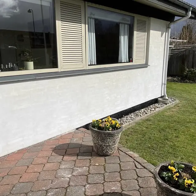 Færdig hvid facade med kalkpuds — sommerlys og blomster